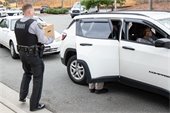 Orange County Sheriff's Office helps distribute Commodity Supplemental Food Boxes. Image of an Orange County officer putting a food box in a recipients car.