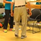 Older man balancing on one foot in exercise studio.