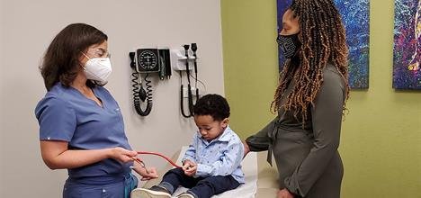 Image of young boy at pediatric office with health care provider and mother