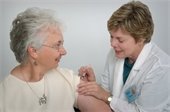 Older woman receiving vaccination from female health care worker.