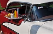 Photo of old classic red/white car with window tray filled with drive-in diner food.