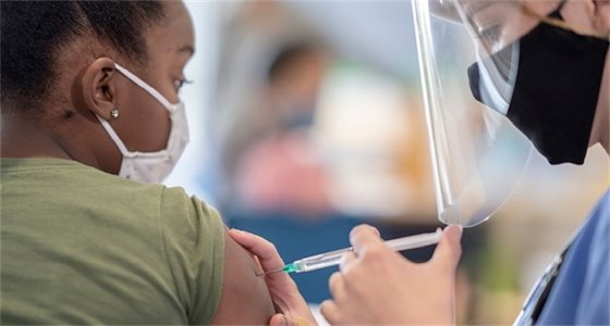 Image of masked Black woman receiving vaccination