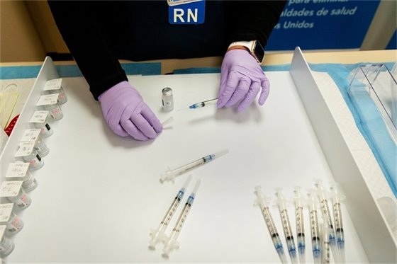 Gloved nurse preparing vaccine doses.