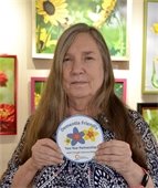 photo of Mary Knox of Margaret Lane Gallery - holding Dementia Friendly Business decal