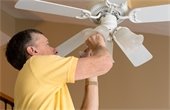 Man repairing ceiling fan - replacing light bulb.