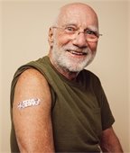 Older white man with sleeve rolled up and band-aid on his arm.