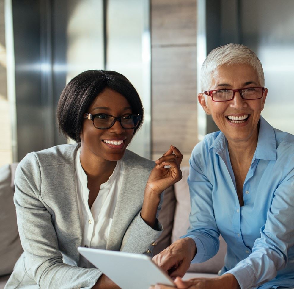 two older woman smiling and holding a tablet