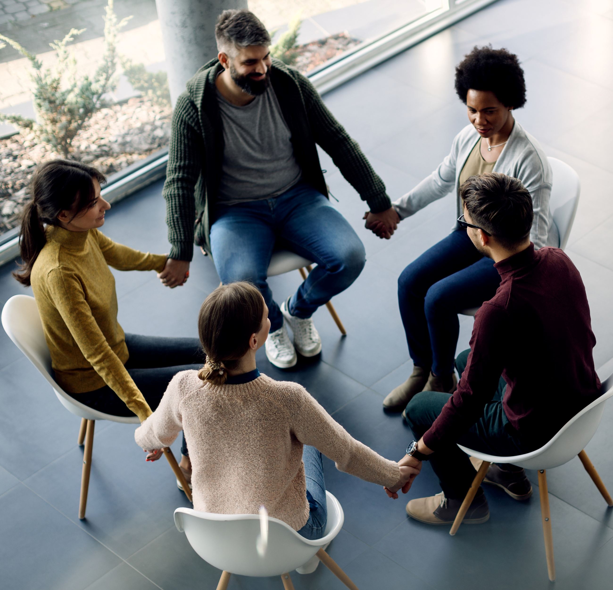 People holding hands sitting in a circle during a therapy session