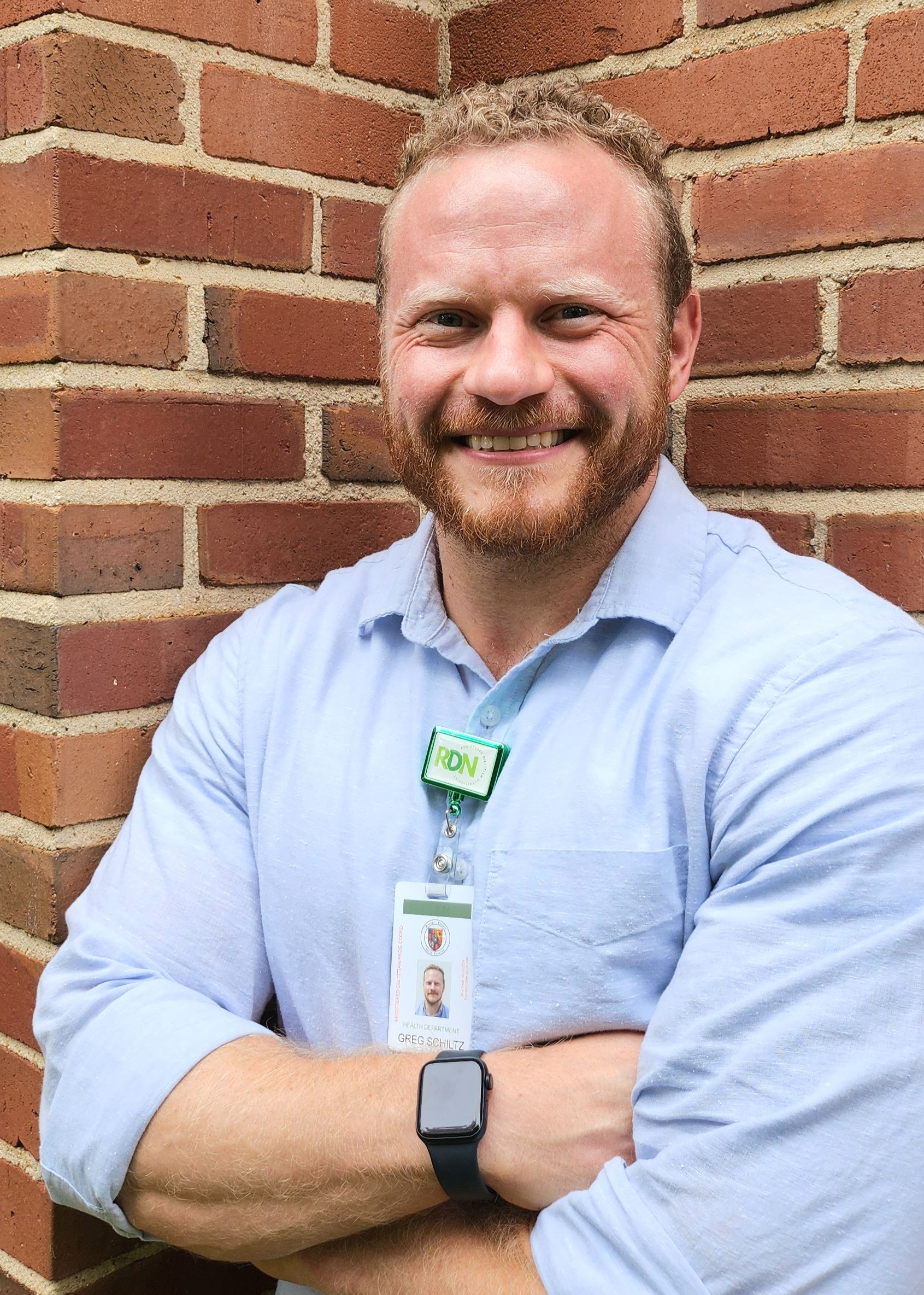 Photo of Greg Schiltz standing near a brick wall