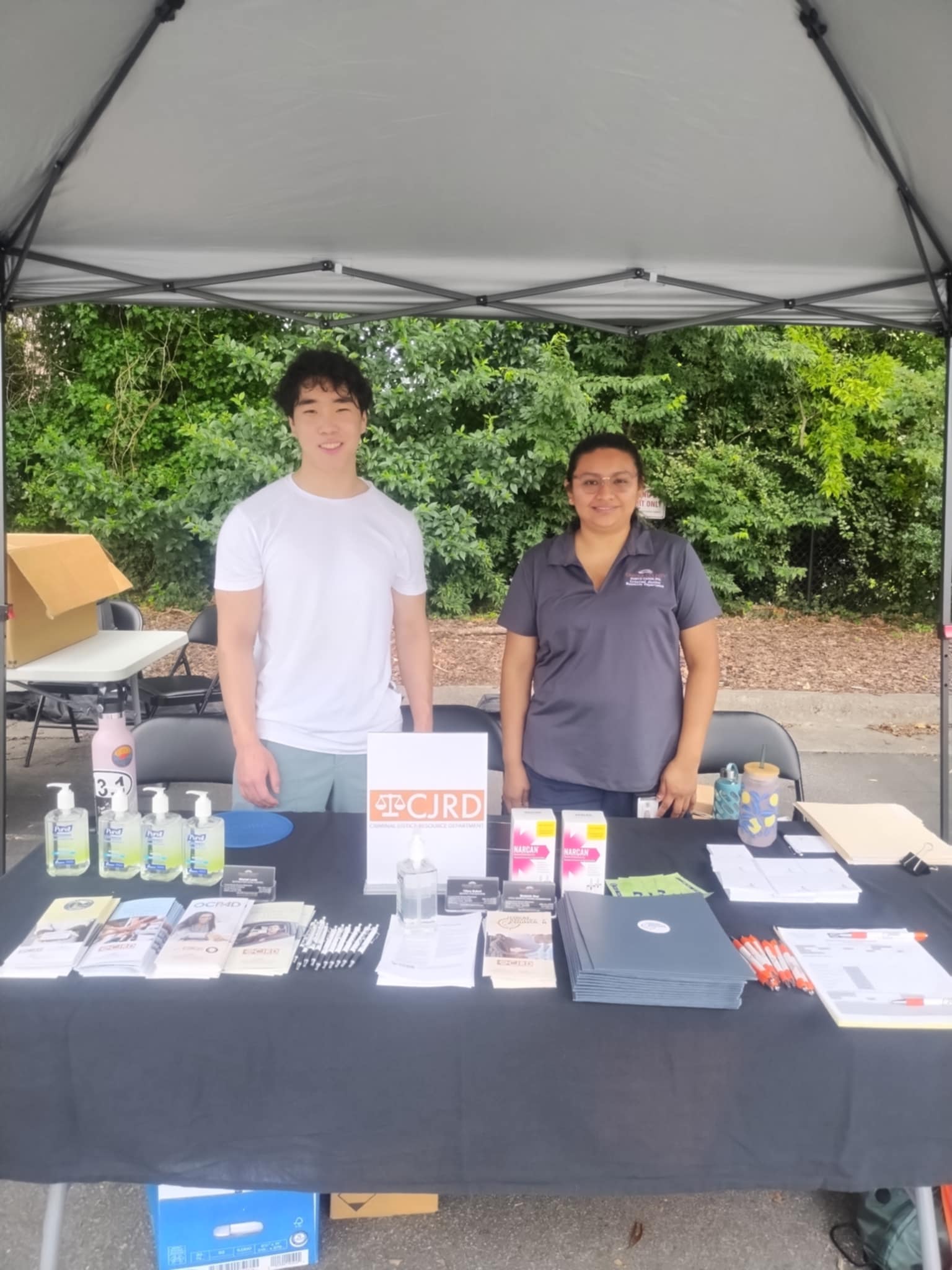 Orion, LRC intern, and Sandra, CJRD grants management coordinator, behind a table at community event