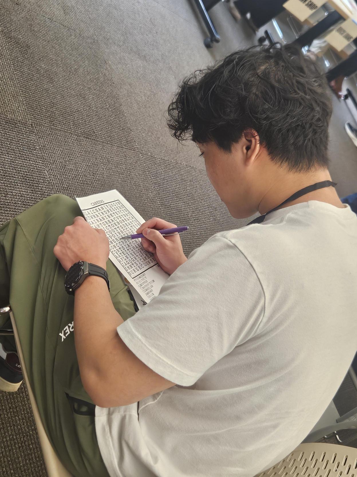 Orion, LRC intern, sitting by himself at Chapel Hill library reentry event, writing something down